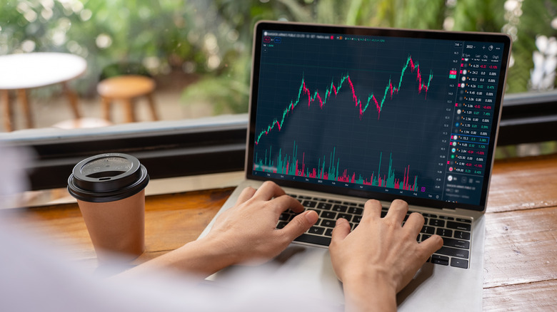Hands typing on a laptop screen while graphs are displayed on the screen.