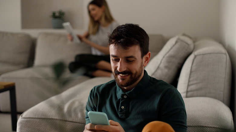 person using smartphone with person using tablet in background