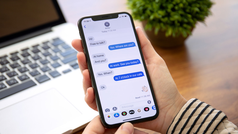 person holding an iPhone showing an iMessage chat