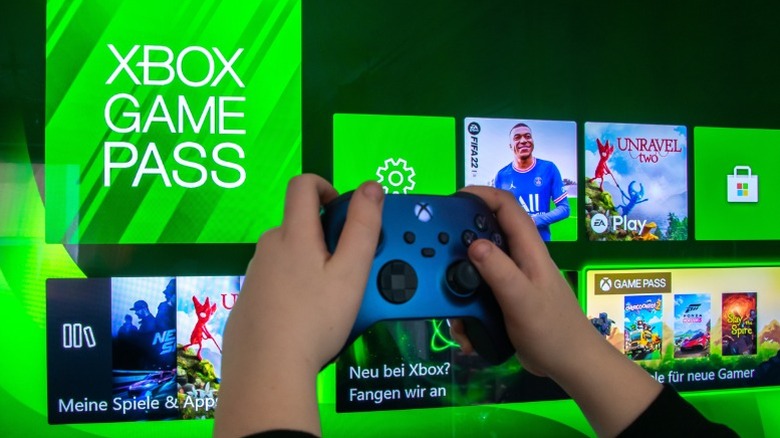 Person holding an Xbox controller in front of a screen