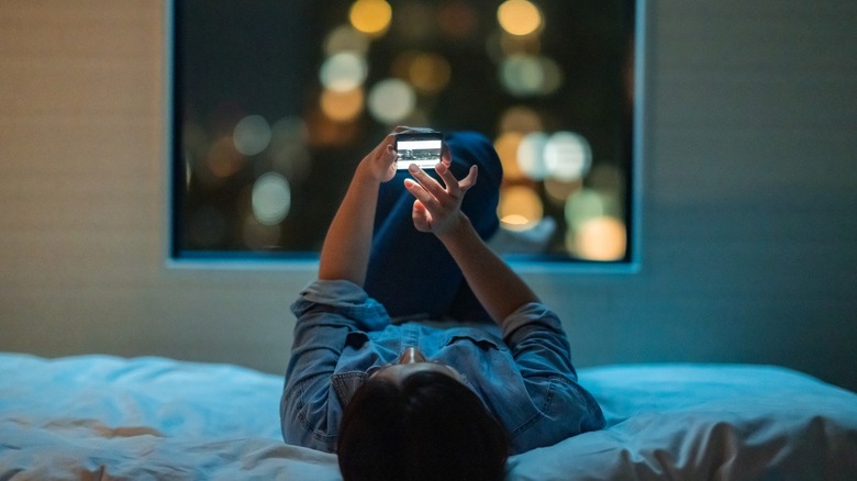 woman using phone in bed