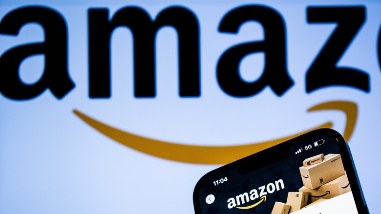 Amazon app on phone in front of slightly out of focus Amazon logo