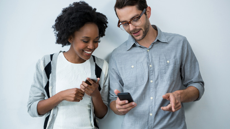 man and woman holding phones