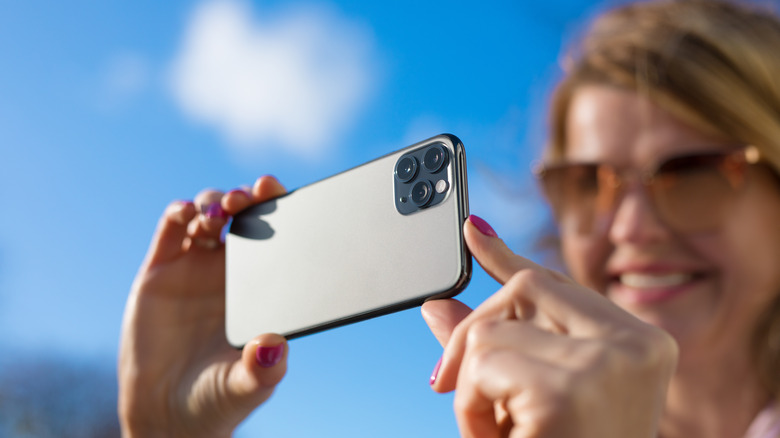 woman taking photo with modern triple-lens camera phone