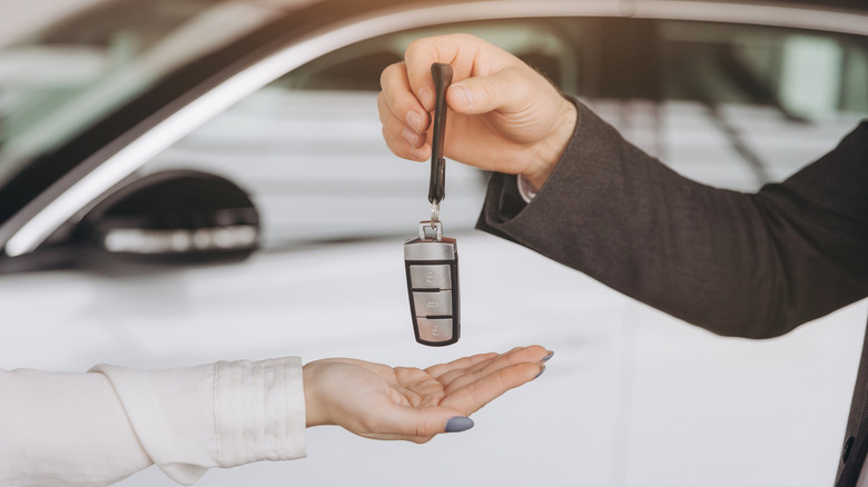 Man handing over a Volkswagen smart key to a woman