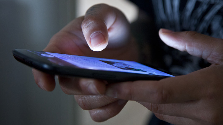 hands holding illuminated smartphone in the dark