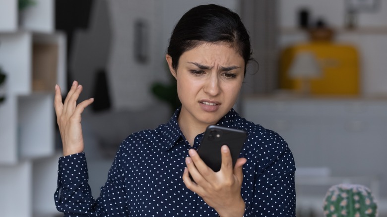 annoyed person frowning at smartphone