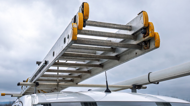 Shot of a heavy-duty ladder affixed to the a truck rack on top of a white vehicle