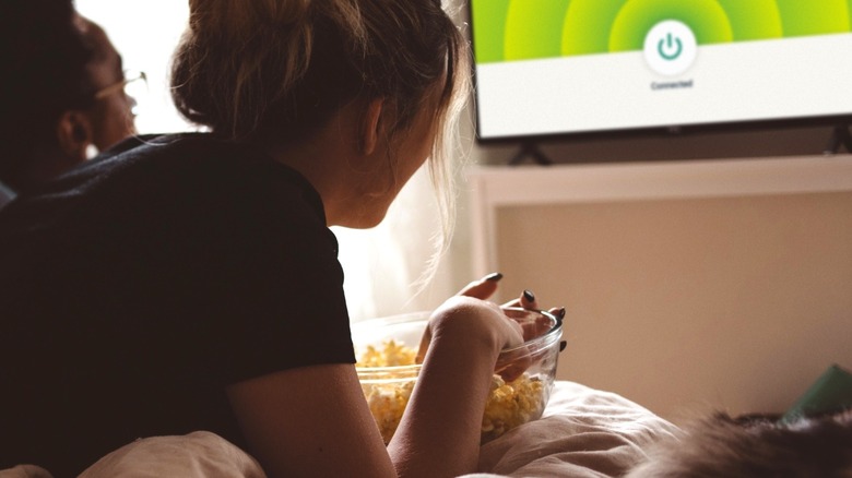 ExpressVPN app on TV while two women watch and enjoy popcorn