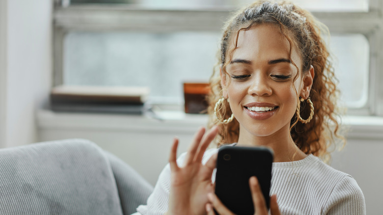Smiling and tapping on smartphone screen