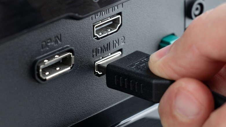 A hand connecting an HDMI cable to the female port on a device