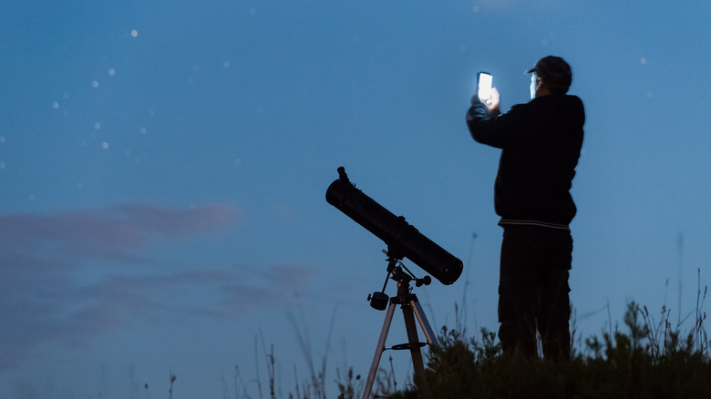 man with a telescope and smartphone