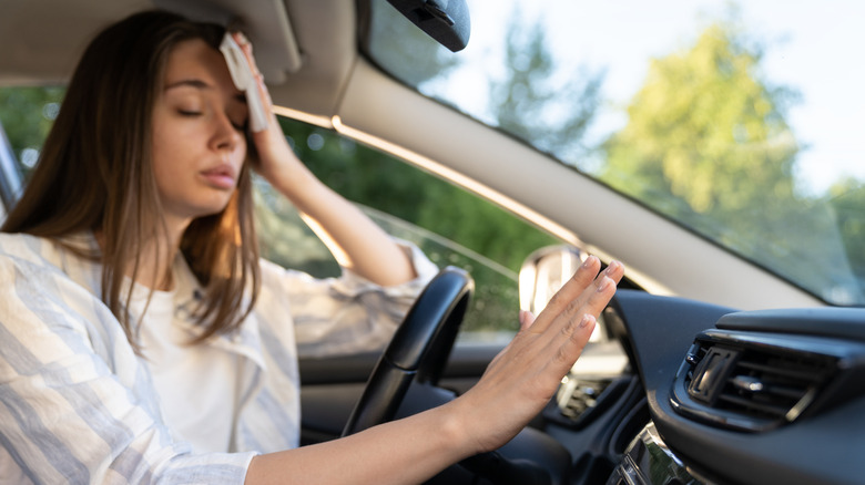 A woman driving car with broken air conditioner in hot summer weather