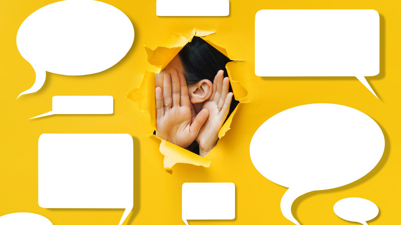 Close-up of a female ear and hands amongst dialogue bubbles showing the concept of eavesdropping.