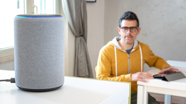 Man staring at and using an Amazon Echo device. 