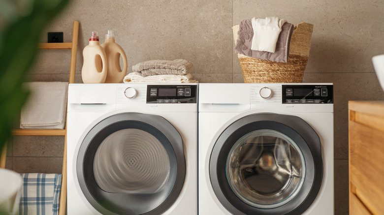 White washing machine and clothes dryer placed side by side inside a laundry room