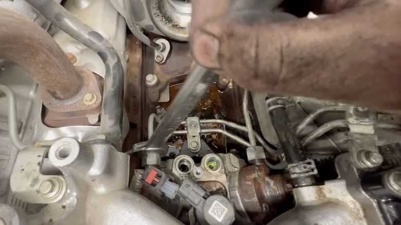 a mechanic works on an engine with cp4 pump exposed