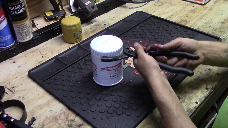 A person demonstrating how to use a set of oil filter pliers