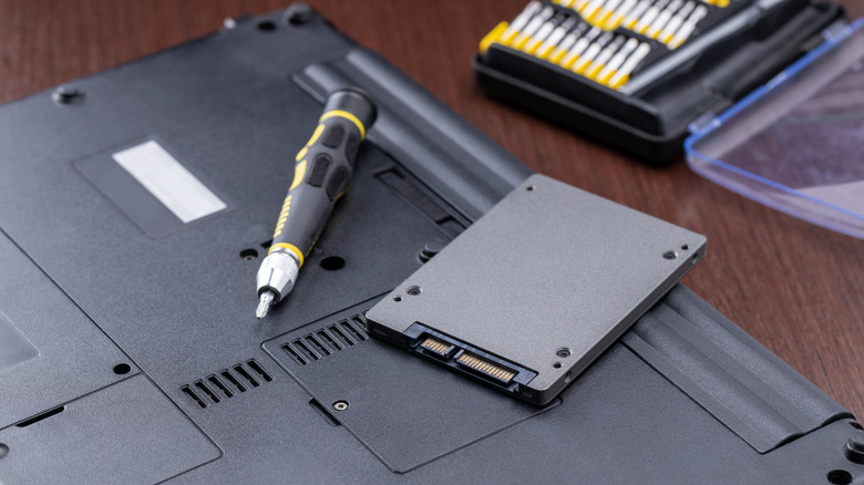 Back of laptop with disk removed and set of screwdrivers