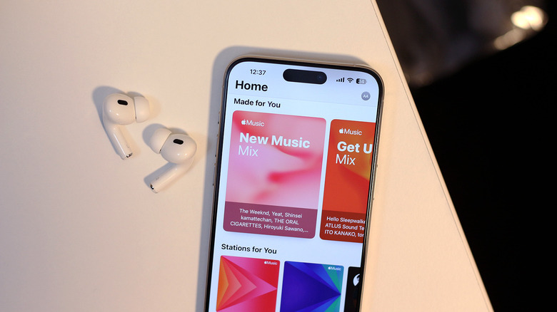 Apple Music app on an iPhone with AirPods next to it