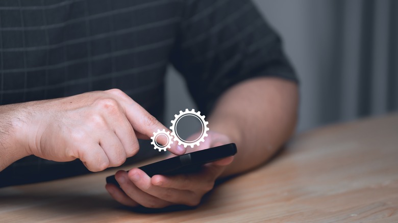 man working on phone with settings icon