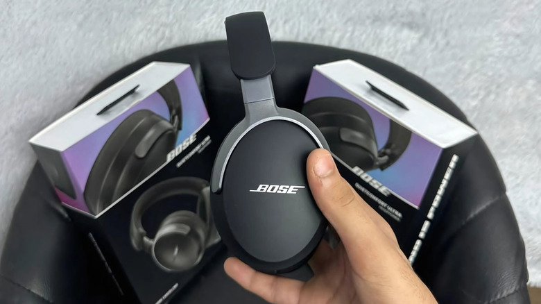 A hand holding a brand new, just removed from the packaging pair of Bose headphones