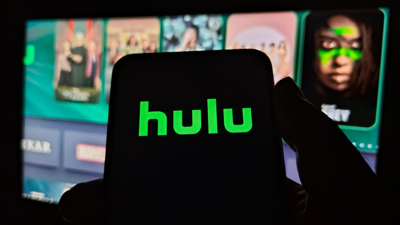 The Hulu logo on a phone in front of a TV.