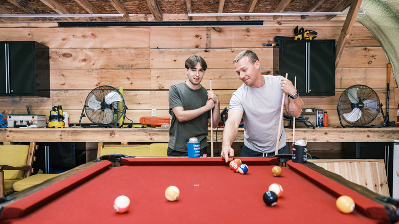 Two young man playing pool inside man cave that seems to be in a converted garage