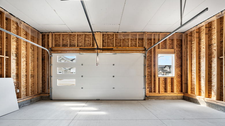 Garage with a white door and a window. The garage is empty and has a lot of space