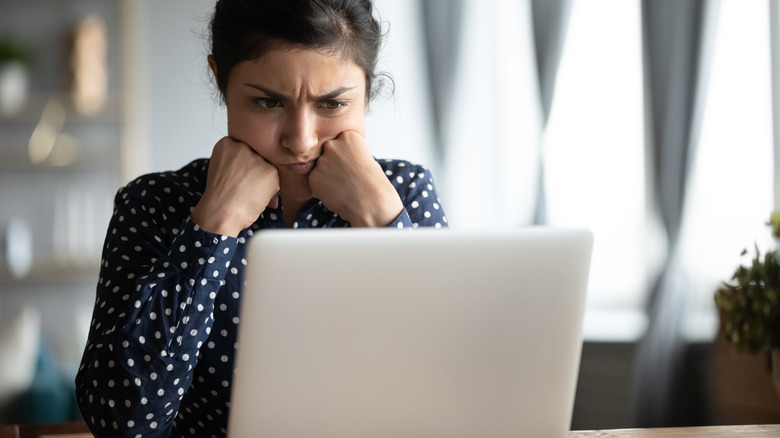 woman looking annoyed at laptop