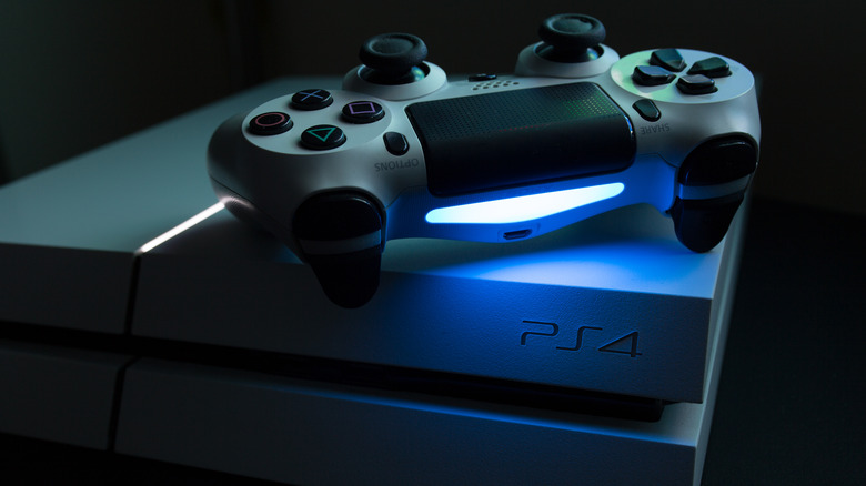 dim photo of a PlayStation 4 console and controller, illuminated by built-in console and controller lights