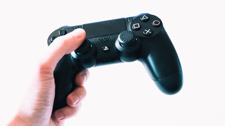 hand holding PlayStation 4 controller on white background