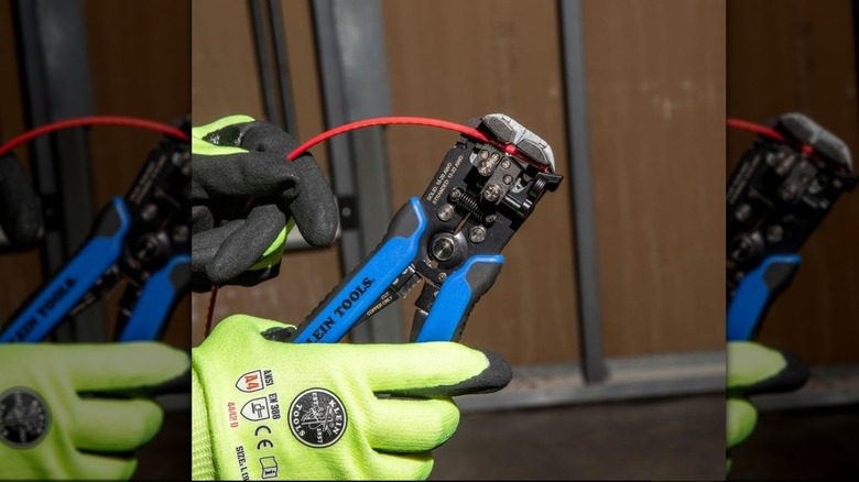 Person with gloves stripping wire with Klein self-adjusting strippers