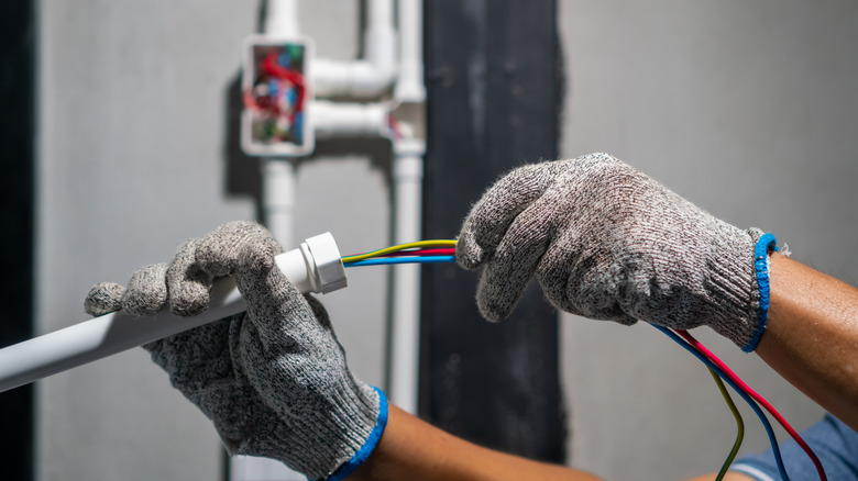 person routing wires through tubes