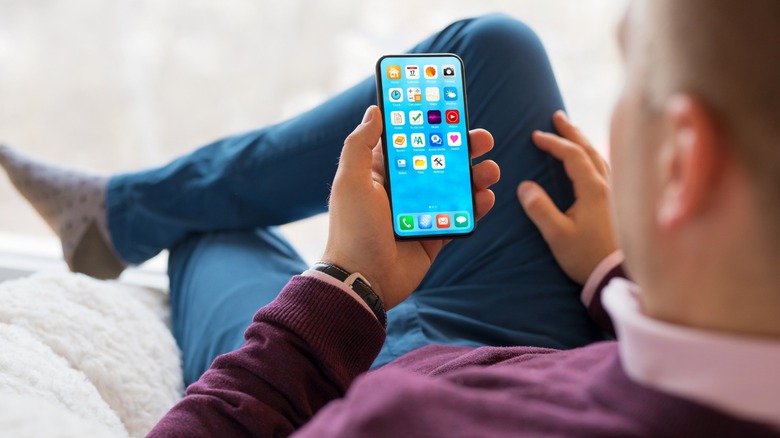 man sitting on couch and looking at an Android phone