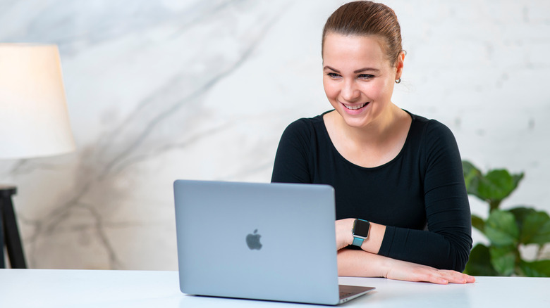 woman smiling at macbook