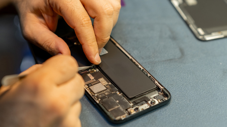 A technician repairing an smartphone with a precision tool