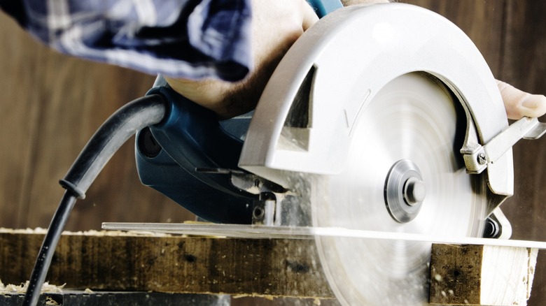 Power saw cutting wood sawdust flying