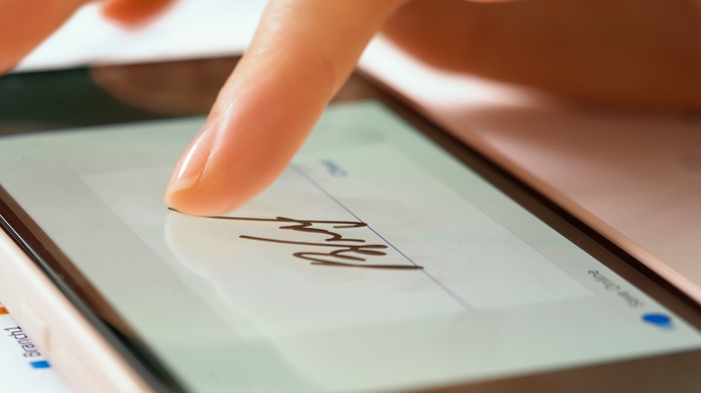 Finger drawing a signature on smartphone screen