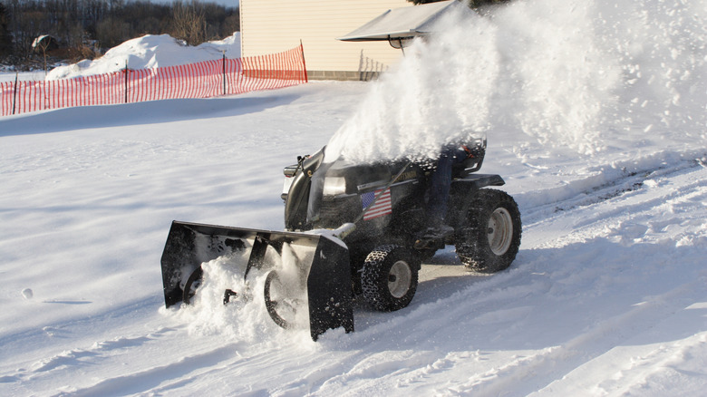 Clearing the driveway of snow with a riding mower