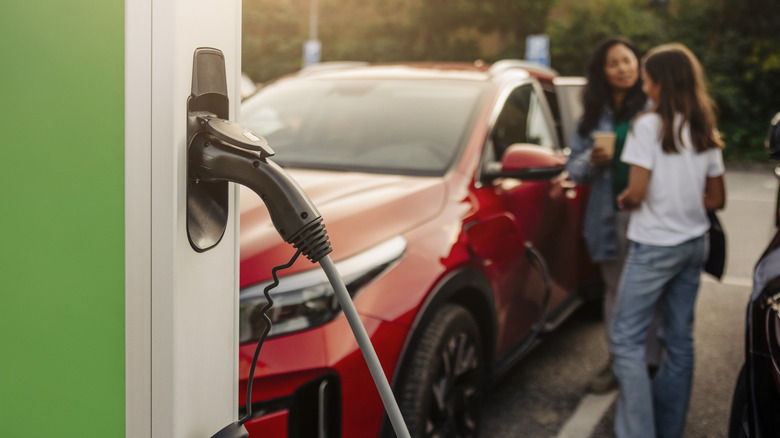 Closeup of EV charger with car and driver in background