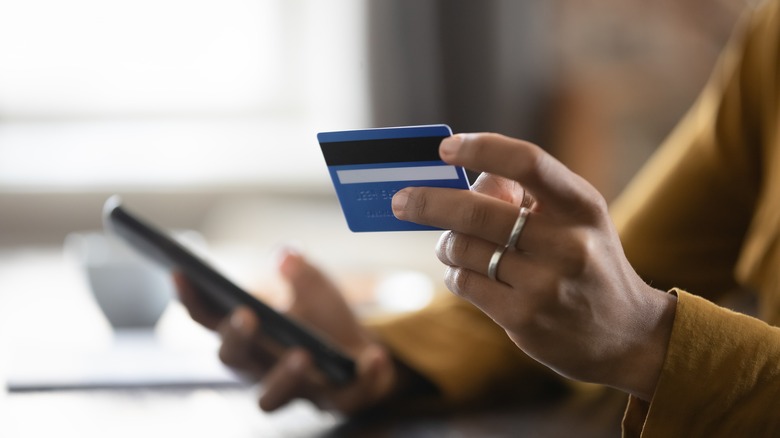 Woman using debit card and mobile phone 