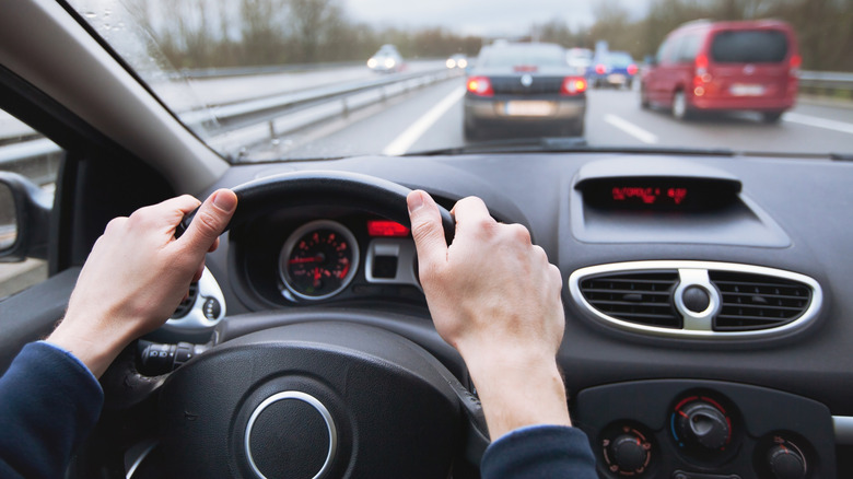 Close-up of a person with their hands on a car's steering wheel.