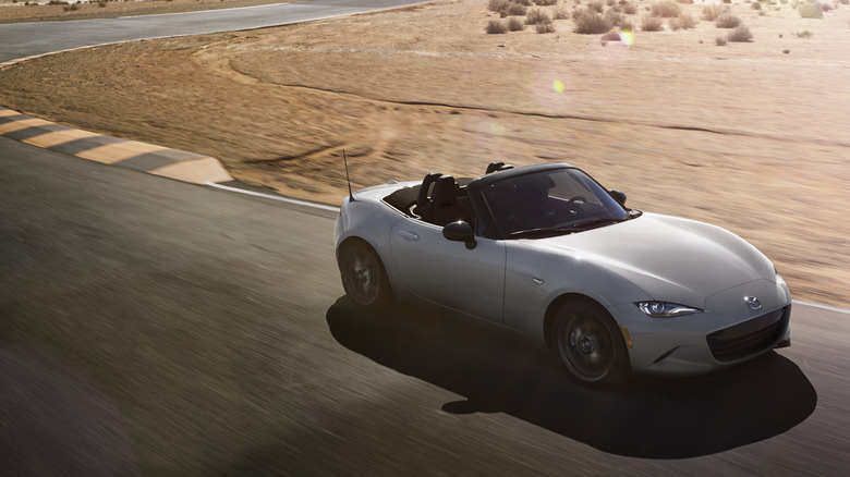 Overhead view of gray Mazda MX-5 Miata driving on desert race track.