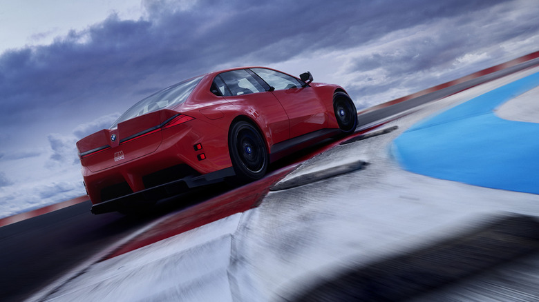 Rear 3/4 view of red BMW M Concept Neue Klasse taking corner on race track.