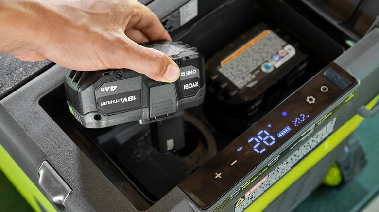 person changing batteries on Ryobi cooler