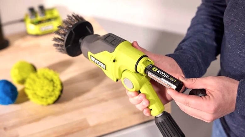 Person putting battery in Ryobi Telescopic Power Scrubber