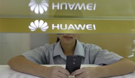 File photo of sales assistant looking at her mobile phone behind a counter at a Huawei booth in Wuhan