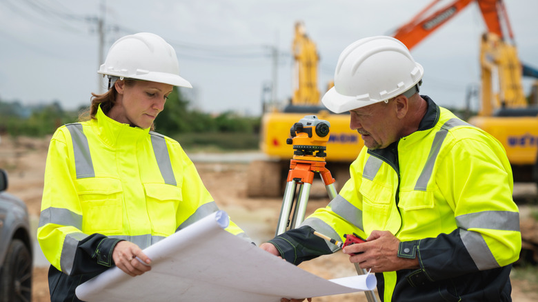 Highway construction workers with road plans in work area