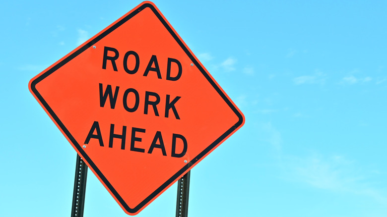 Orange Road Work sign against blue sky